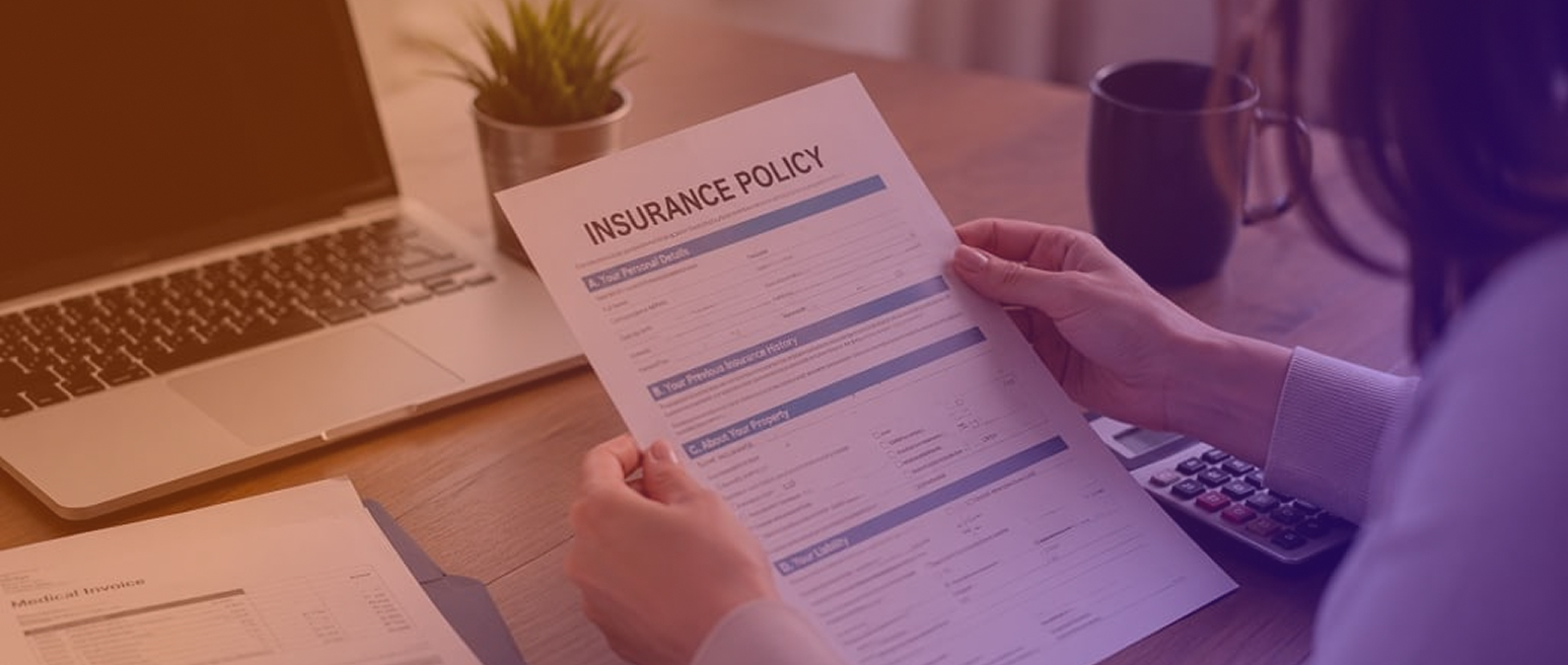 Человек изучает документ Insurance Policy рядом с ноутбуком и калькулятором